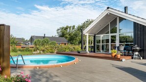 Una casa moderna con piscina, zona de barbacoa y terraza.