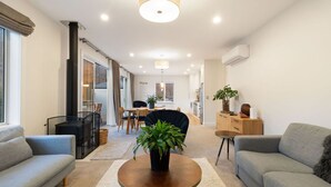 A modern living room with a sofa, a coffee table, and a dining area with a table and chairs. - Duff's Cottage-fabulous location-comfort +style (Arrowtown)