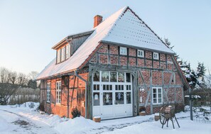 Et traditionelt bindingsværkshus med et stejlt saddeltag, store vinduer og en trædør.
