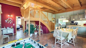 A spacious living area with a wooden staircase, a dining table set for four, and a kitchen area with modern appliances. - 3 bedroom beautiful home in Thandorf (Thandorf)