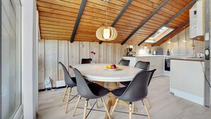 Un comedor con una mesa redonda, sillas negras y techo de madera.