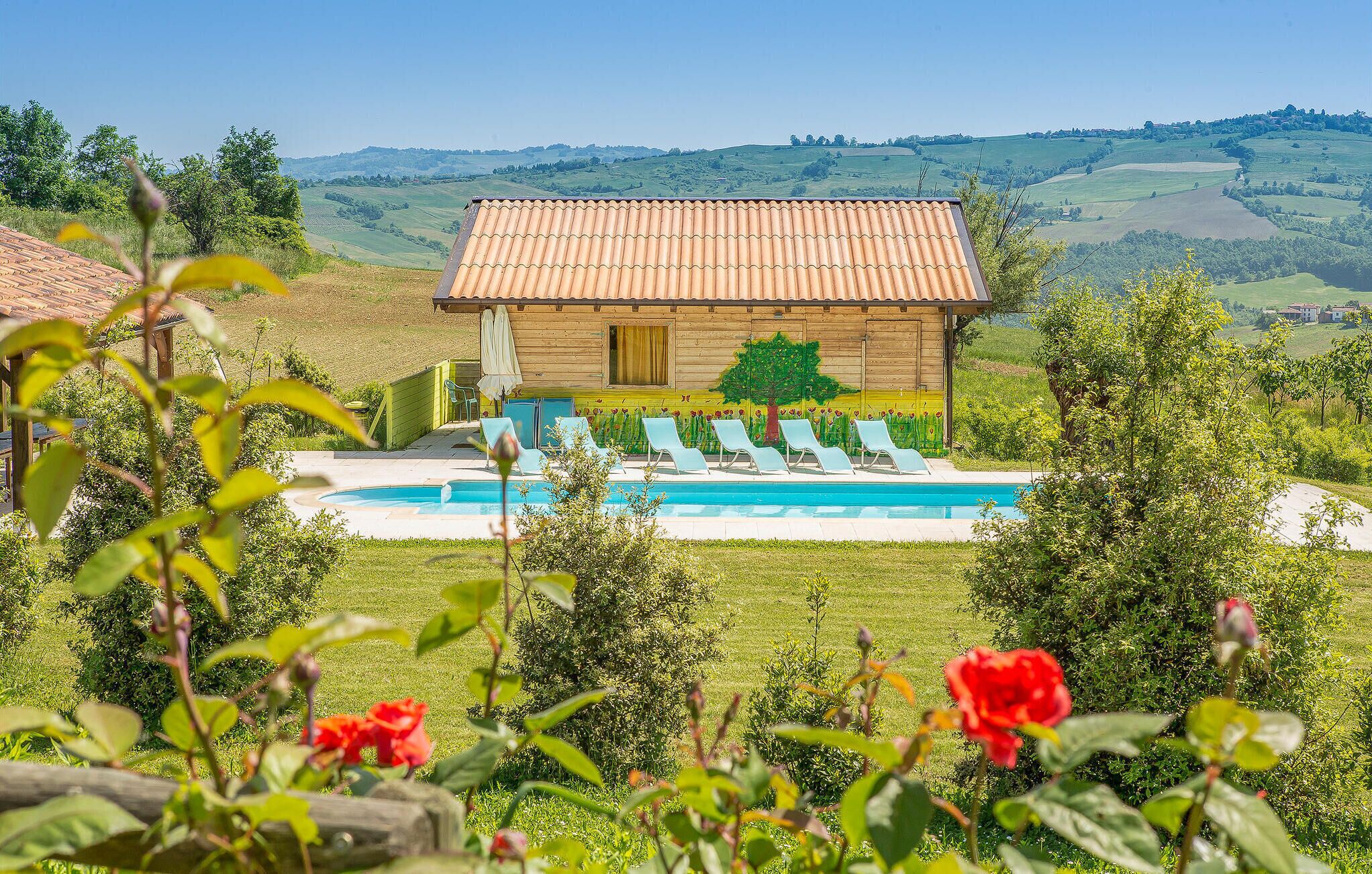 A wooden house with a tiled roof, a swimming pool, and lounge chairs.