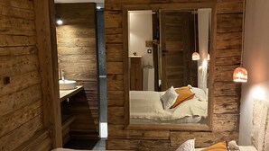 A wooden room with a bed, a mirror, and a sink.