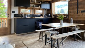 A rustic kitchen with wooden beams, a black countertop, and a wooden dining table with benches.