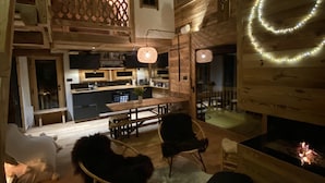 A cozy, rustic interior with a wooden ceiling, a fireplace, and a dining area.