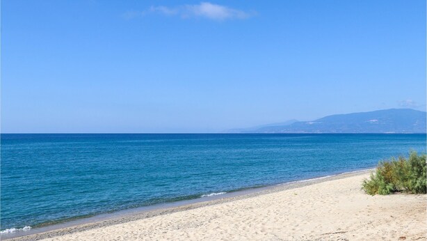 Une plage à l’eau d’un bleu limpide et au rivage sablonneux.