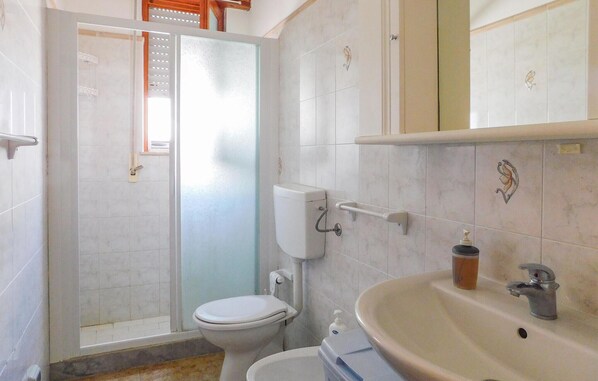 Une salle de bain avec des toilettes, un lavabo et une douche.
