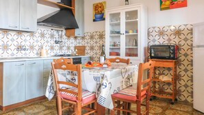 Une cuisine de taille réduite comprenant une table à manger, des chaises, un four à micro-ondes et un placard.