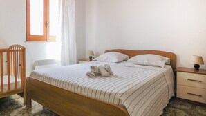 Un lit bien fait, avec une literie à rayures, une tête de lit en bois et une table de chevet avec une lampe.