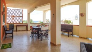 Une vaste terrasse dotée d’un espace repas, d’un banc et offrant une vue sur la mer.