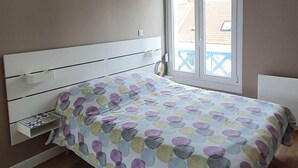 Une chambre à coucher avec un lit, un ventilateur de plafond, une fenêtre donnant sur un beau paysage et un plancher en bois.
