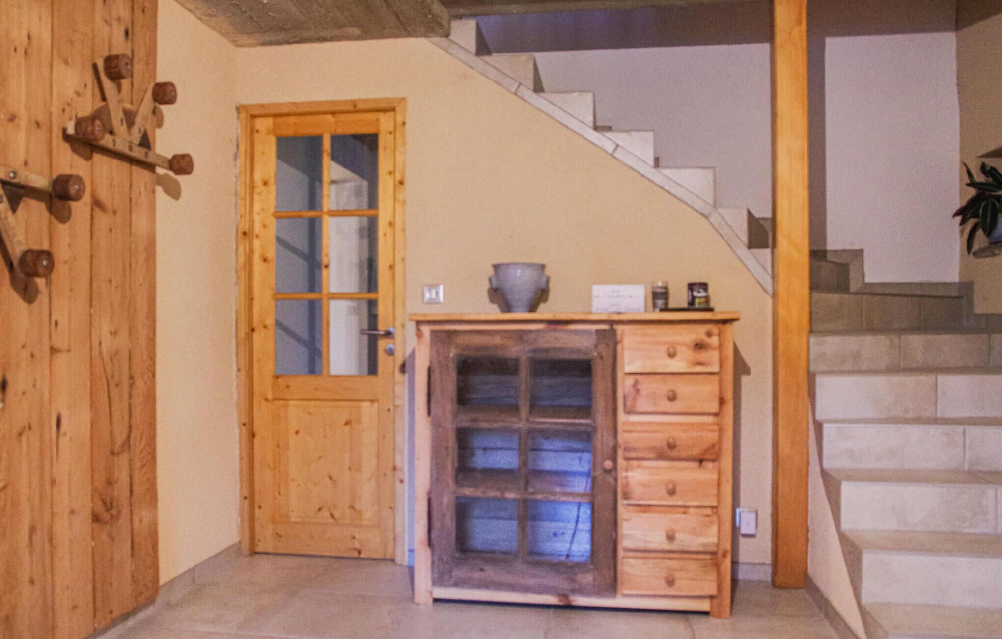 A wooden door with glass panels, a small wooden cabinet with drawers, and a staircase with a handrail.