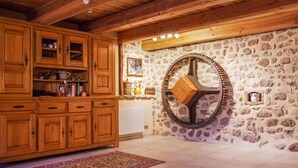 Une cuisine rustique avec des meubles en bois, un mur en pierre et une grande roue décorative.