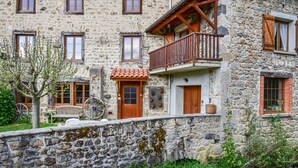 Un bâtiment en pierre doté de nombreuses fenêtres, d’un balcon en bois et d’une porte de style traditionnel.
