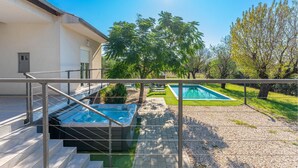 A modern outdoor pool area with a hot tub, a staircase leading to a covered deck, and a clear view of the surrounding trees and grass. - Gorgeous home in Prkos (Prkos)