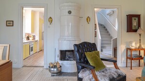 A room with a fireplace, a staircase, and a dining area visible through an open door. - Nice home in Hallstavik with sauna (Hallstavik)