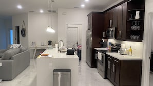 A modern kitchen with a central island, stainless steel appliances, and dark wooden cabinets. - Gorgeous build on fresh water canal - very private-heated pool (Cape Coral)