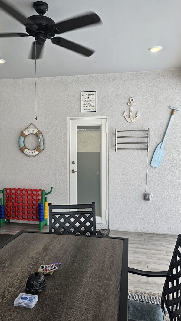 Una habitación con ventilador de techo, una puerta con letrero que dice 'Welcome Friends', una decoración de ancla montada en la pared y una tabla de remo.