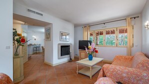 A living room with a sofa, a TV, a fireplace, and a dining area in the background. - Lovely home in Fayence (Fayence)
