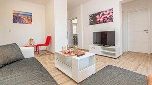 Ett modernt vardagsrum med en soffa, en röd fåtölj, ett soffbord och en tv som står på ett tv-bord.