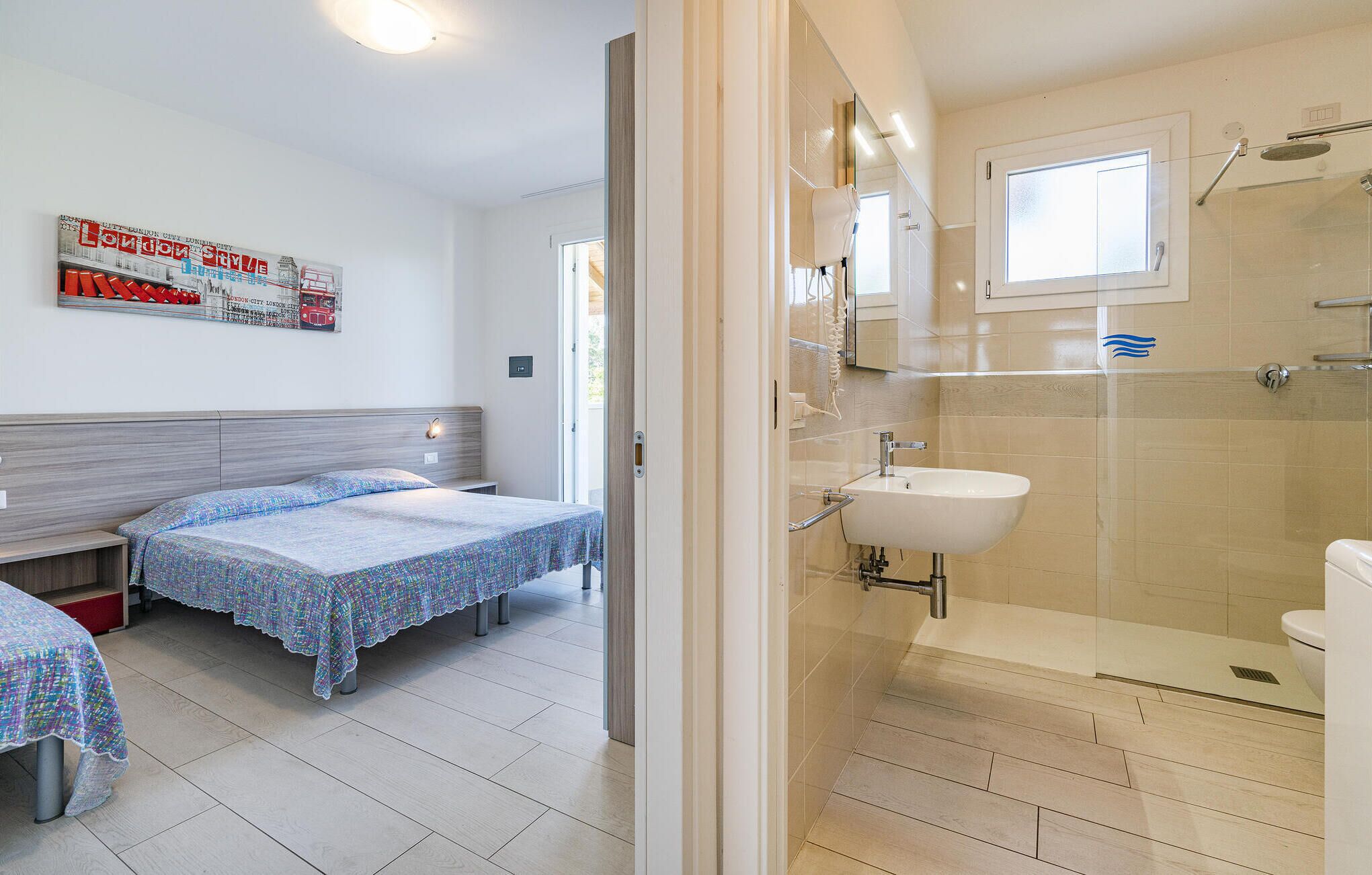 Une chambre d’hôtel avec deux lits, une salle de bain avec douche et une affiche accrochée au mur.