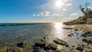 A coastal scene with clear skies, sunlight reflecting off the water, and rocky terrain. - Amazing apartment in Trecastagni with WiFi (Trecastagni)