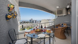 Un balcone con un tavolo apparecchiato per consumare un pasto, sedie e vista sulla città.