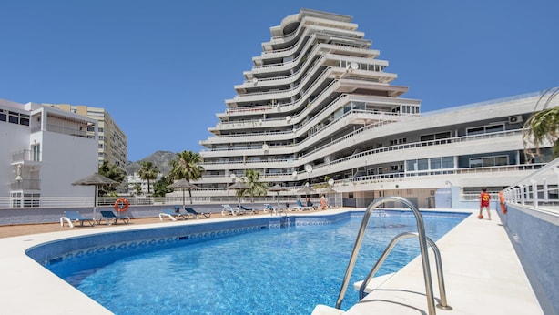 Una piscina con acqua cristallina e azzurra, circondata da lettini e un galleggiante.