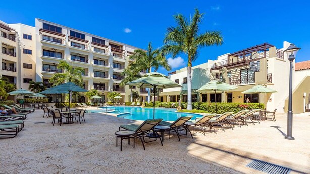 A resort pool area with sun loungers, umbrellas, and a clear blue pool.