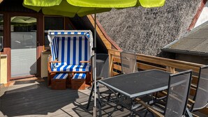A deck with a blue and white striped lounge chair, a small table, and a metal chair. - Beach front home in Mariendorf with WiFi (Mariendorf)