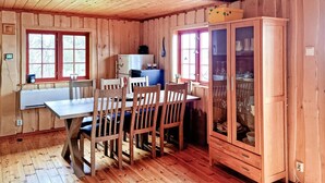 Un interior de madera con una mesa de comedor, sillas, un refrigerador y un armario.