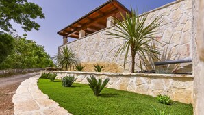 A stone building with a wooden pergola, surrounded by well-maintained grass and various plants. - Beach front home in Pridraga (Pridraga)