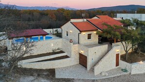 A stone house with a swimming pool, a red-roofed structure, and a view of mountains. - Beach front home in Pridraga (Pridraga)