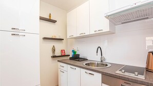 A modern kitchen with white cabinets, a stainless steel sink, and a built-in oven. - Cozy apartment in Brodarica with WiFi (Brodarica)