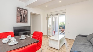 A modern living room with a dining area, a TV, and a balcony with a chair. - Cozy apartment in Brodarica with WiFi (Brodarica)