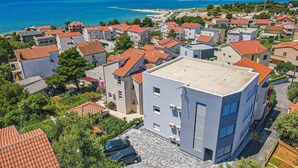 A residential area with buildings featuring red-tiled roofs, surrounded by greenery and a coastal view. - Cozy apartment in Brodarica with WiFi (Brodarica)
