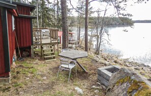 A cabin with a deck, outdoor seating, and a view of a lake. - Nice home in Herräng with sauna (Herräng)