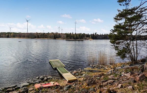 Uitzicht op een meer met een steiger, rustig water en windturbines op de achtergrond.