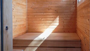 Una sauna de madera con techo inclinado y un banco.