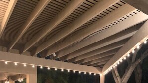 Un patio al aire libre con una parrilla, sillas y luces colgantes.