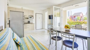 Een modern appartement met een kitchenette, een eethoek met een tafel en stoelen, en een balkon met uitzicht op de omgeving.
