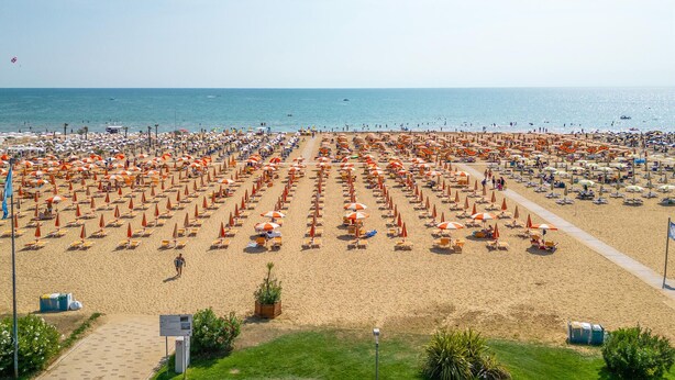 Een strand met rijen zonnebedden en parasols.