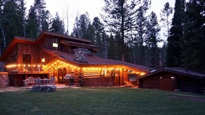 Eine Blockhütte mit Veranda, Sitzgelegenheiten im Freien und einem Kamin aus Stein.