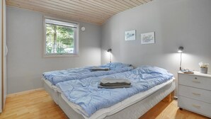 A bedroom with a large bed, a window, a bedside table with a lamp, and a dresser. - Pet friendly home in Væggerløse (Væggerl øse)