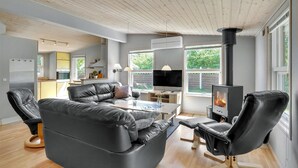 A modern living room with a sofa, chairs, a TV, and a wood-burning stove. - Pet friendly home in Væggerløse (Væggerløse)