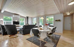 Uma sala de estar moderna com sofá, cadeiras, mesa de jantar e televisão.
