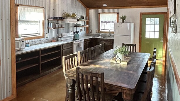 A spacious kitchen with a large wooden table and chairs, a ceiling fan, and a green door. - Hummingbird Cabin, located down Riverroad close to local shops and restaurants! (Concan)