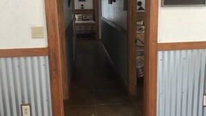 A narrow hallway with a bed at the end, wooden trim, and a small shelf with decorative items. - Hummingbird Cabin, located down Riverroad close to local shops and restaurants! (Concan)