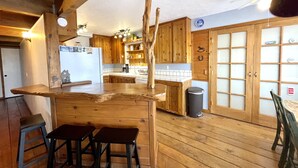 Eine rustikale Küche mit Holzausbau, einer Bar mit Hockern und einem großen Fenster.