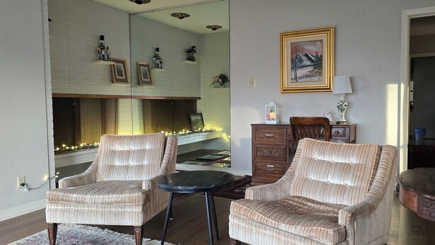 A living room with two striped armchairs, a small round table, a wooden cabinet, and a framed picture on the wall.